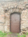 Antique steel riveted door in a stone wall with a stony frame