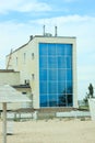 Beautiful apartments with glass windows, modern architecture house by the sea, sandy beach, blue cloudy sky.