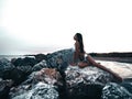 Beautiful, appealing young model with an attractive slim appealing body in bikini is lying and posing on the rocks at the sunset.