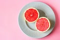 Beautiful appetizer fresh red grapefruit citrus fruit with half slice on blue plate and pink background close up top view natural Royalty Free Stock Photo