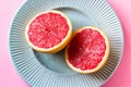 Beautiful appetizer fresh red grapefruit citrus fruit with half slice on blue plate and pink background close up top view natural Royalty Free Stock Photo