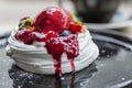 Beautiful appetizing dessert on a table in a cafe. Meringue with berry ice cream. Close-up