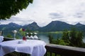 Beautiful Aps landscape with lake, green mountains, valley, forest and table with glases of a restaurant foreground