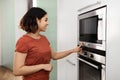 Beautiful arab female turning on electric oven in kitchen Royalty Free Stock Photo