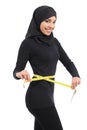 Beautiful arab saudi fitness woman measuring her waist with a tape measure