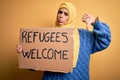 Beautiful arab woman wearing islamic hijab holding banner with refugees welcome message with angry face, negative sign showing Royalty Free Stock Photo