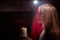 Beautiful arabian girl with candles in red room full of rich fabrics and carpets in sultan harem. Photo shoot of woman