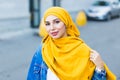 Beautiful Arabic muslim woman wearing yellow hijab, stylish female face portrait over city street. Royalty Free Stock Photo