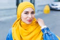 Beautiful Arabic muslim woman wearing yellow hijab, stylish female face portrait over city street. Royalty Free Stock Photo