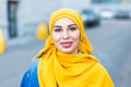 Beautiful Arabic muslim woman wearing yellow hijab, stylish female face portrait over city street. Royalty Free Stock Photo