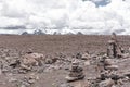 Beautiful arid landscape with stone stack apacheta, snowy mountains and cloudy sky in Peruvian Altiplano near Colca Canyon