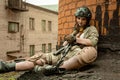 Beautiful army girl with rifle in camouflage clothes in urban scene, getting rest.