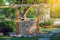 Beautiful artesian well made by stones and wood in peaceful garden atmosphere. Retro stone water well in rural area. Garden