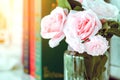 Beautiful artificial pink roses in glass vase on a white table with blured image of three books Royalty Free Stock Photo
