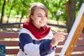 Beautiful artist draws a picture in a good mood outdoors.