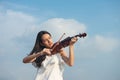 Beautiful asia girl with black hair and white dress playing on a violin Royalty Free Stock Photo