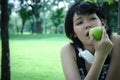 Beautiful Asia sport woman holding green apples and walking in park.