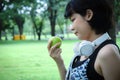 Beautiful Asia sport woman holding green apples and walking in public park