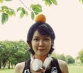 Asia sport woman holding orange and walking in public park.