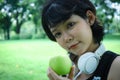 Beautiful Asia sport woman holding green apples and walking in public park