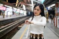 Beautiful asia woman looking at watch standing in lines waiting sky train on platform at night Royalty Free Stock Photo