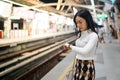 Beautiful asia woman looking at watch standing in lines waiting sky train on platform at night Royalty Free Stock Photo