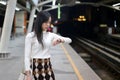 Beautiful asia woman looking at watch standing in lines waiting sky train on platform at night Royalty Free Stock Photo