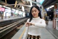 Beautiful asia woman looking at watch standing in lines waiting sky train on platform at night Royalty Free Stock Photo