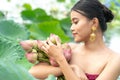 Beautiful asia women wearing traditional Thai dress and sitting on wooden boat in flower lotus lake. Her hands are holding a pink Royalty Free Stock Photo