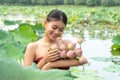 Beautiful asia women wearing traditional Thai dress and sitting on wooden boat in flower lotus lake. Her hands are holding a pink Royalty Free Stock Photo