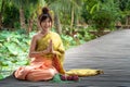 Beautiful asia women wearing traditional Thai dress and sitting on wooden bridge. Her hand is in the respect hands in thailand sty Royalty Free Stock Photo