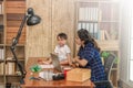 Beautiful Asian business mom is using a laptop  while spending time with her cute baby boy at home for quarantine from virus Royalty Free Stock Photo