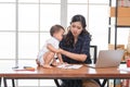 Beautiful Asian business mom is using a laptop  while spending time with her cute baby boy at home for quarantine from virus Royalty Free Stock Photo