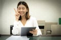 Beautiful asian business woman is encourage yourself to work and sitting showing victory sign on her cheek.