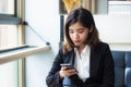 A beautiful Asian business woman executive relaxing in coffee shop holding and using an application in her smart phone Royalty Free Stock Photo