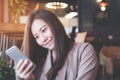 A beautiful Asian business woman holding , using and looking at smart phone in modern cafe Royalty Free Stock Photo