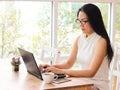 Asian business woman with long black hair wearing eye glasses working in coffee shop , typing on computer. Royalty Free Stock Photo