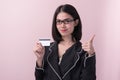 Beautiful asian business woman showing thumb up to recommend credit card in her hand isolated on pink background Royalty Free Stock Photo