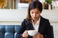 A beautiful asian business woman sitting on sofa and looking cup of hot coffee in her hand. Royalty Free Stock Photo