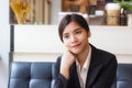 A beautiful asian business woman sitting on sofa and looking or thinking something with her smiling Royalty Free Stock Photo