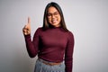 Beautiful asian business woman wearing casual sweater and glasses over white background showing and pointing up with finger number Royalty Free Stock Photo