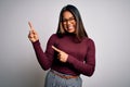 Beautiful asian business woman wearing casual sweater and glasses over white background smiling and looking at the camera pointing Royalty Free Stock Photo