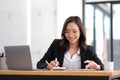 Beautiful Asian businesswoman analyzes charts using laptop calculator at the office.