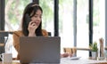 Beautiful Asian businesswoman analyzes charts using laptop calculator and talking the phone at the office.