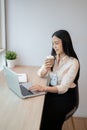 Beautiful Asian businesswoman is having a morning coffee while working on her laptop in the office Royalty Free Stock Photo