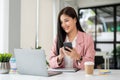 A beautiful Asian businesswoman looking at her laptop screen while using her smartphone Royalty Free Stock Photo