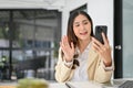 Beautiful Asian businesswoman say Hi and talking with someone on a video call via her phone Royalty Free Stock Photo