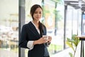 Beautiful Asian businesswoman standing in front of her office with a cup of coffee in her hands Royalty Free Stock Photo