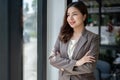 A beautiful Asian businesswoman stands with her arms crossed, daydreams Royalty Free Stock Photo