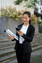 A beautiful Asian businesswoman is texting someone while standing outside of the building Royalty Free Stock Photo